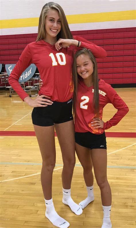 Two Female Volleyball Players Posing For A Photo On The Court With Their Arms Around Each Other