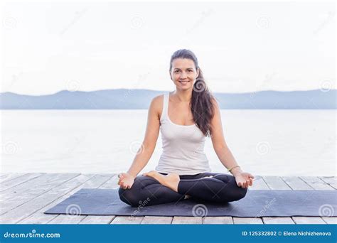 Young Attractive Smiling Woman Practicing Yoga On A Lake Stock Photo