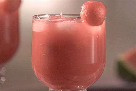 A Close Up Of A Drink In A Glass With Watermelon Slices On The Side
