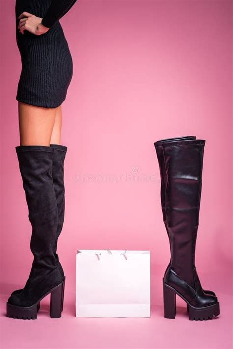 The Girl Stands In Black Jackboots On Her Feet On A Pink Background In