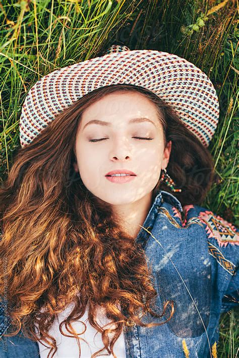 sensual portrait of a beautiful woman with hat laying on the grass by aleksandar novoselski