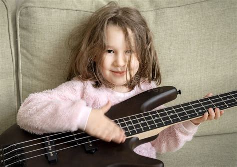Kid Playing Bass Guitar At Home Portrait Of Little Baby Girl Sitting