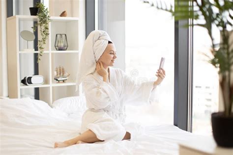 Adult Female Taking Selfie On Mobile While Sitting On Bed Stock Image