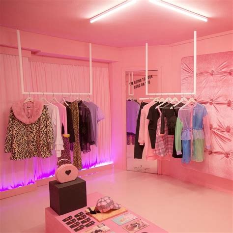 A Room With Pink Lighting And Clothes On Display