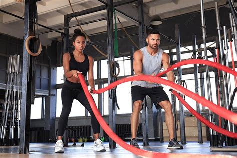A Fit Couple Engaged In Functional Training Using Battle Ropes At A Gym