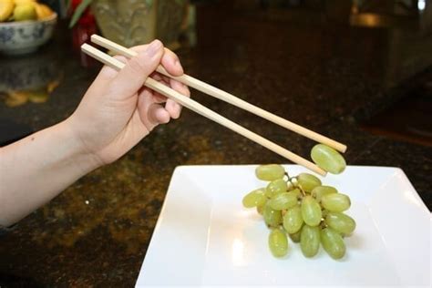 Hold both chopsticks together in the crook between the base of your thumb and index finger until you're ready to dig in. How to Use Chopsticks | The Woks of Life