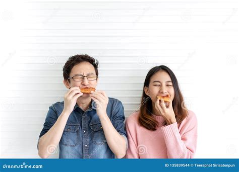 Attractive Asian Hungry Couple Eating Pizza Or Fast Food With Smile And Tasty Facial Expression