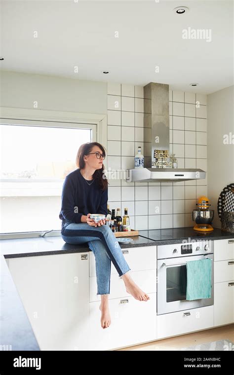 Young Woman Sitting On Kitchen Counter Stock Photo Alamy