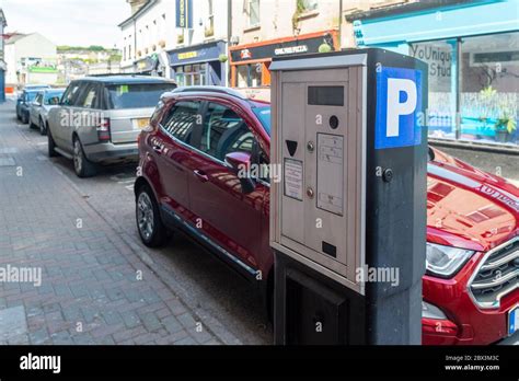 Cars Parked In The Street Next To A Coin Operated Parking Meter In
