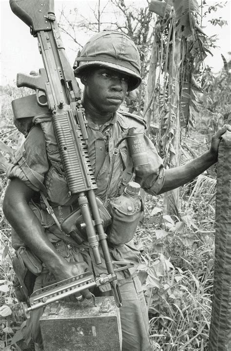 Carrying Both His Weapon And Boxes Of Ammunition An M 60 Machine