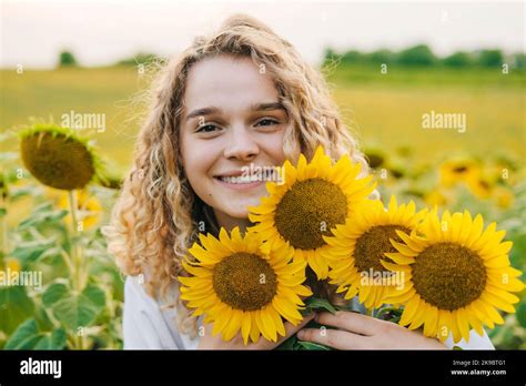 Happy farm girl embracing flowers in a field of blooming sunflowers