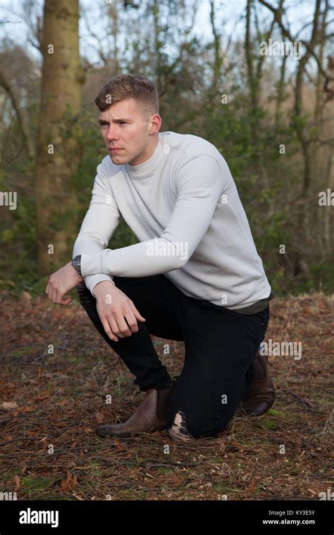 Blonde Good Looking Caucasian Young Man Squatting In The Woods In