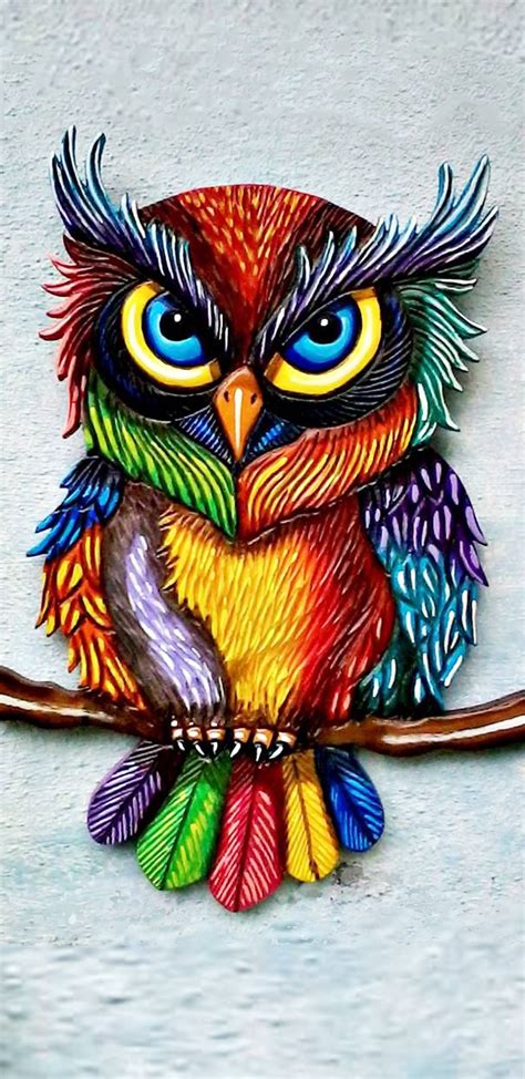 A Colorful Owl Sitting On Top Of A Tree Branch With Blue Eyes And