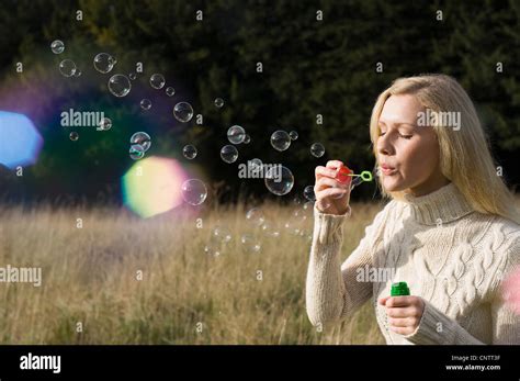 Woman Blowing Bubbles In Wheatfield Stock Photo Alamy