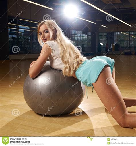 Seductive Blonde Female Model Posing Leaning On Silver Balance Ball
