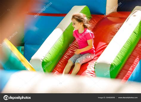 Niña Deslizándose Por Una Diapositiva Inflable Fotografía De Stock