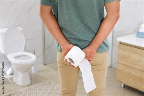 Man With Toilet Paper Suffering From Hemorrhoid In Rest Room Closeup