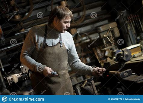 The Portrait Of Blacksmith Preparing To Work Metal On The Anvil Stock