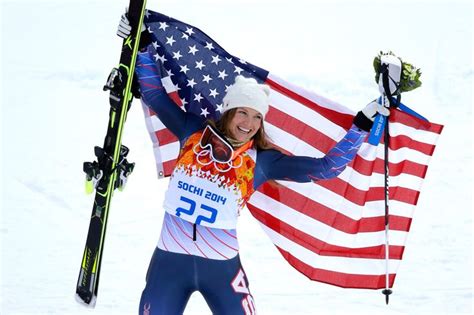 A Woman Holding Up An American Flag And Skis