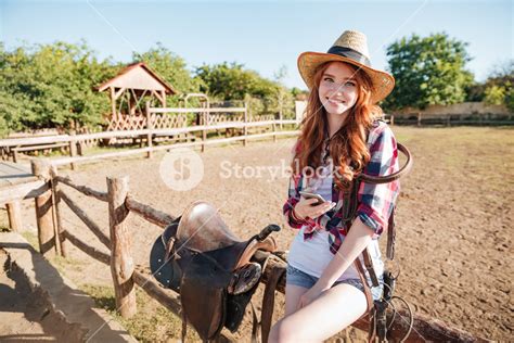 Smiling Pretty Young Woman Cowgirl Standing And Using Mobile Phone On