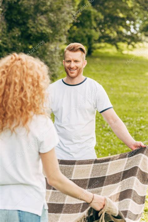 happy redhead couple looking each other holding plaid picnic park stock picture affiliate