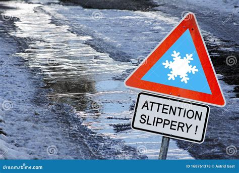 An Icy Road In Winter With A Sign Attention Slippery Stock Photo