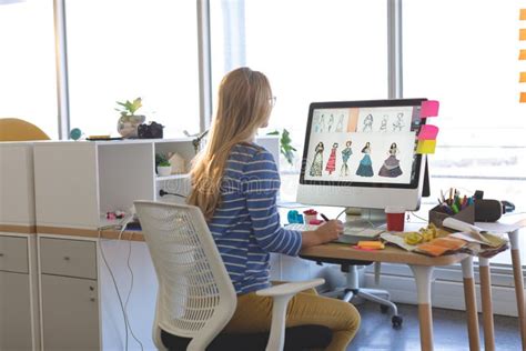 Female Fashion Designer Using Graphic Tablet While Working At Desk