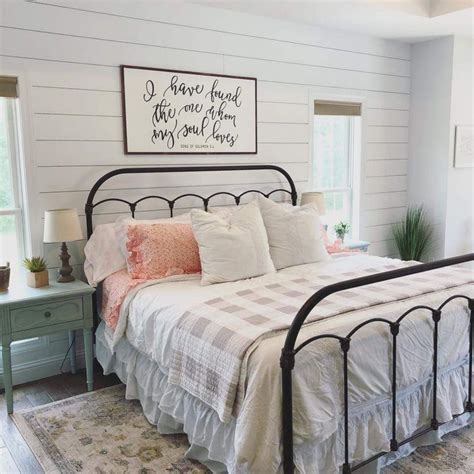 Skip the tufted headboard and instead decorate with a shelf laden with accent pieces you love. Farmhouse style bedroom. Wrought iron bed frame. Check blanket throw, shiplap walls, wooden ...