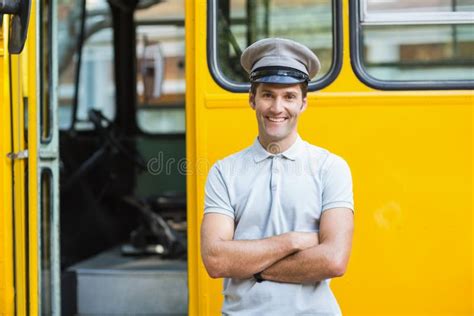 Smiling Bus Driver Standing With Arms Crossed In Front Of Bus Stock