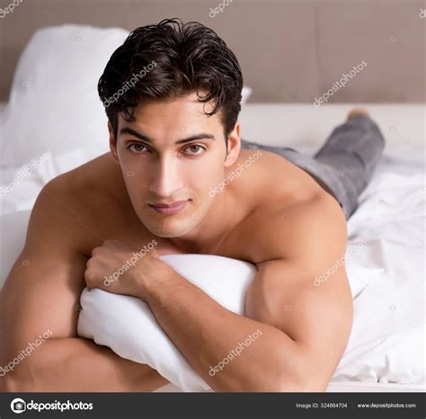 Ung snygg bar överkropp kille visar naken överkropp sexig på sängen på