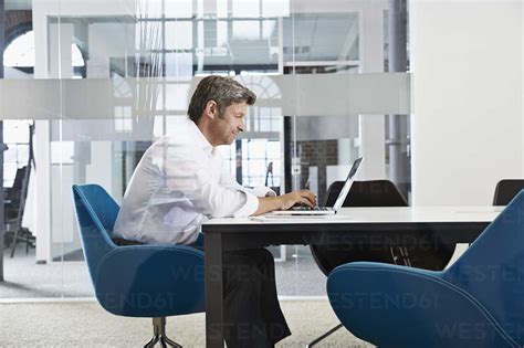 Businessman Using Laptop In Conference Room Stock Photo
