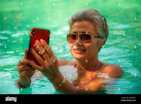 attractive and happy middle aged asian indonesian woman in bikini swimming at tropical luxury