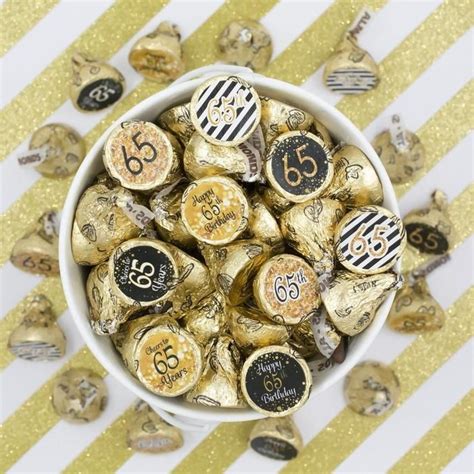 A White Bowl Filled With Gold Foiled Chocolates On Top Of A Striped