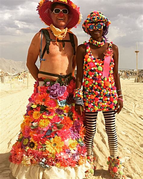 Two People Dressed In Colorful Clothing And Hats On The Beach One Is