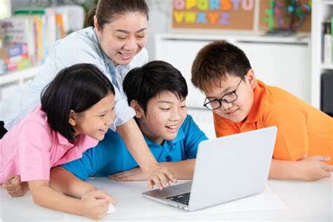 Teacher And Cute Asian Children Using Laptop Computer Together Stock
