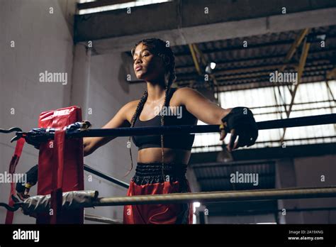 Female Boxer With Eyes Closed Leaning On Ropes In Boxing Ring At Boxing