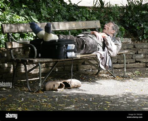 Elderly Man Sleeping On A Park Bench On A Sunny Morning In June Stock