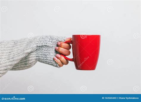 Woman`s Hand In Cozy Sweater Holding A Red Coffee Mug Stock Image