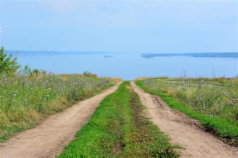 Premium Photo A Dirt Country Road Leads To The Horizon With The Sea