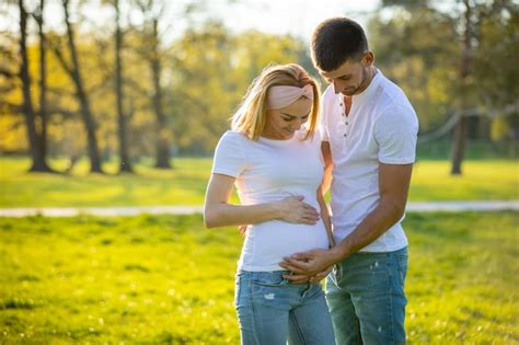 premium photo husband touching pregnant wife belly while standing in park