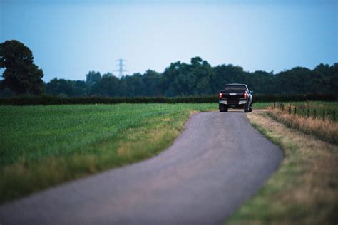 Pickup Truck Driving On Country Road In Evening Stock