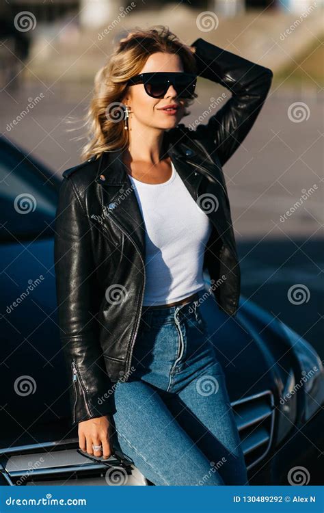 Portrait Of Young Blonde Woman In Sunglasses Standing Next To Black Car