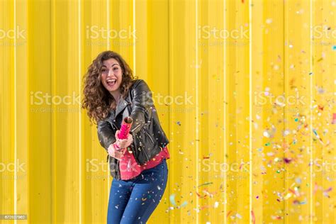 Young Woman Having Fun With Confetti Over Yellow Background Stock Photo