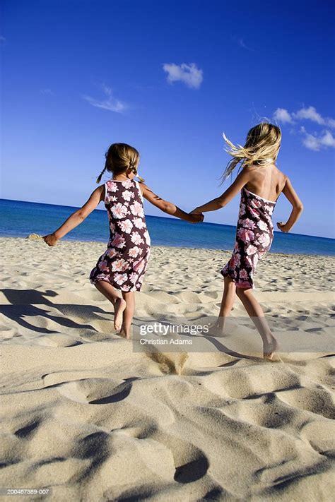 Sisters Running On Beach Holding Hands Side View High Res Stock Photo