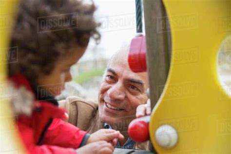 Smiling Grandfather Playing With Grandson At Playground Stock Photo