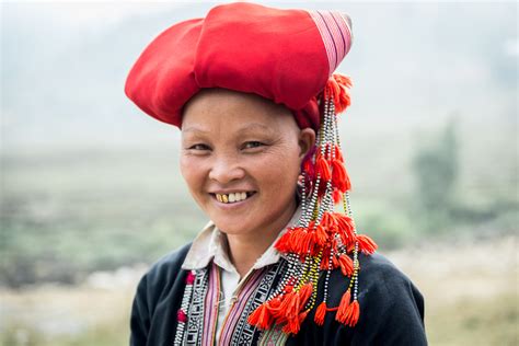 a-woman-dressed-in-traditional-red-hmong-clothing,-poses-outside