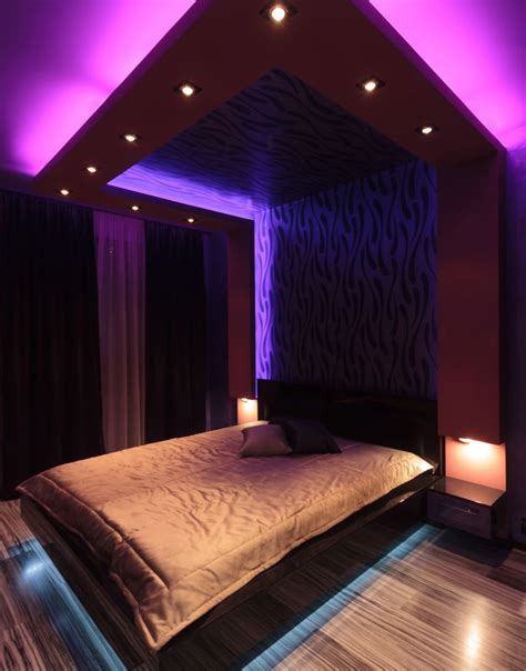 modern bedroom with purple neon mood lighting gray walls and large headboard purple bedroom