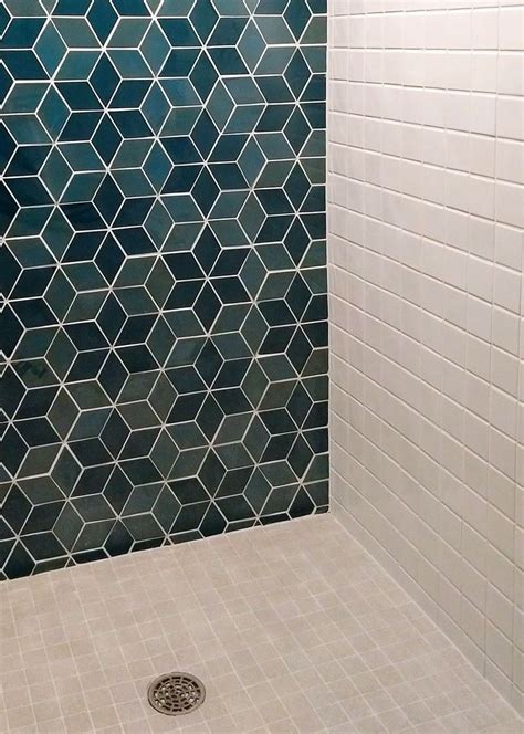 A White Tiled Shower Stall With Blue And Green Tiles On The Wall Along