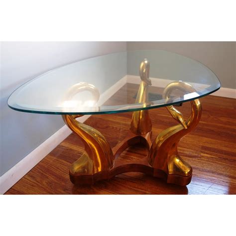 Metal base in a blackened brass finish. Brass Swan & Glass Coffee Table | Chairish
