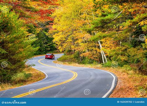 Car Driving Through Winding Road With Autumn Foliage Stock Photo